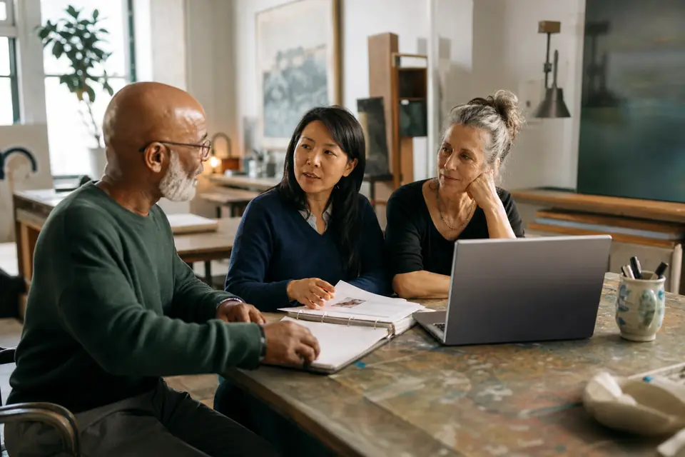 Nonprofit board members reviewing a policy binder at an arts studio worktable.