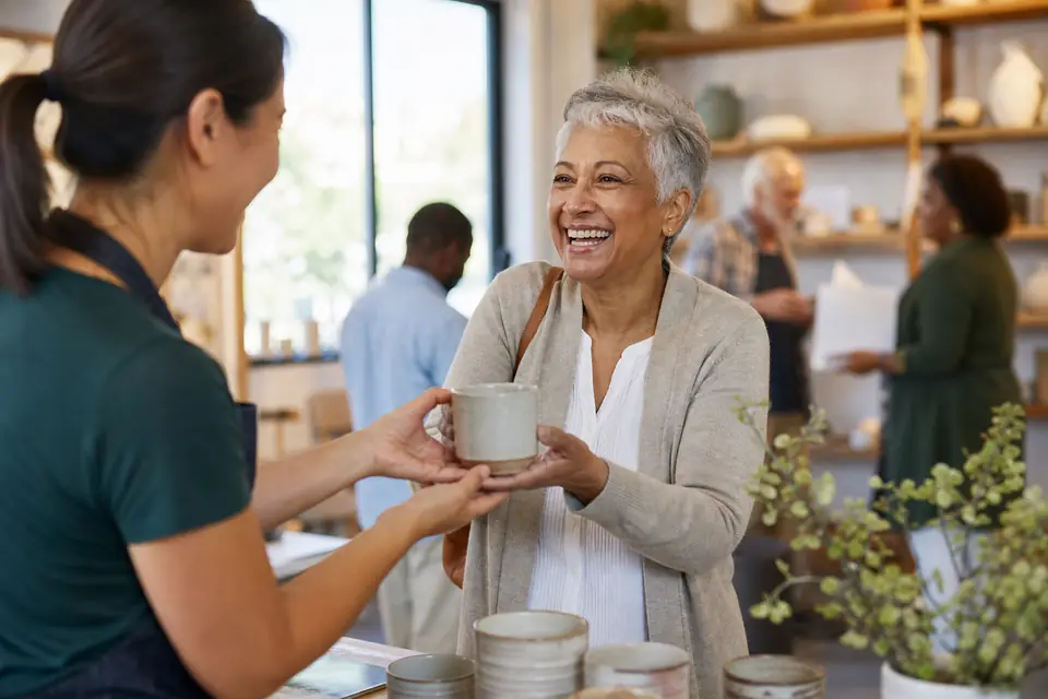 Volunteer handing a ceramic mug to a donor at an arts studio fundraiser