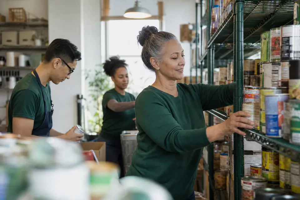 Volunteers stocking shelves with donated canned food at a neighborhood food pantry